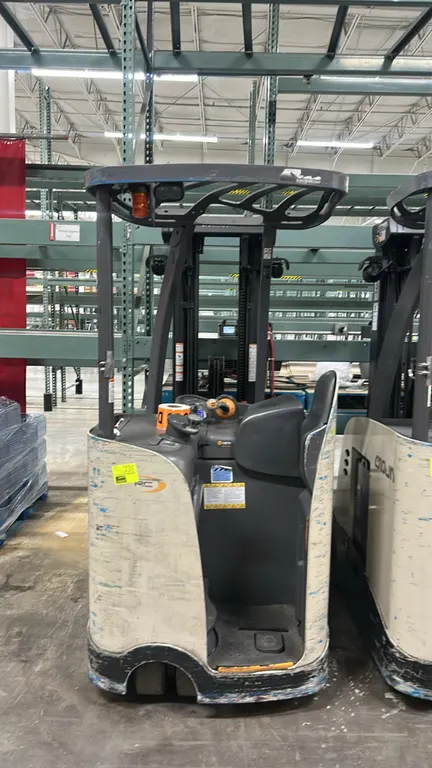 Crown RC5515-30 electric stand-up counterbalanced forklift. Features overhead guard, amber strobe light, work light, operator backrest, forks, and a C