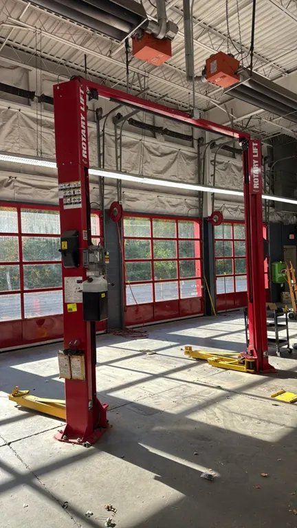 Rotary Lift SPOA10N1500 two-post asymmetric vehicle lift. Features 10,000 lb capacity, overhead crossbeam, swing arms with lift adapters, and electric