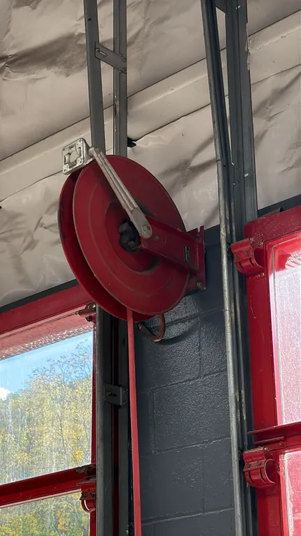 Retractable air hose reel with hose. Features steel construction, spring-rewind mechanism, 4-way roller hose guide, and red air hose. Wall-mounted.