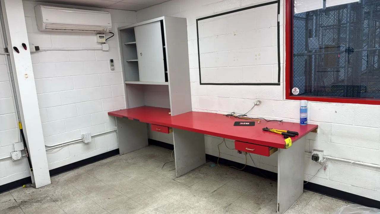 Laminate work desks. Features red laminate tops, gray laminate panel bases, overhead storage hutches with shelves and cubbies, and under-mount drawers