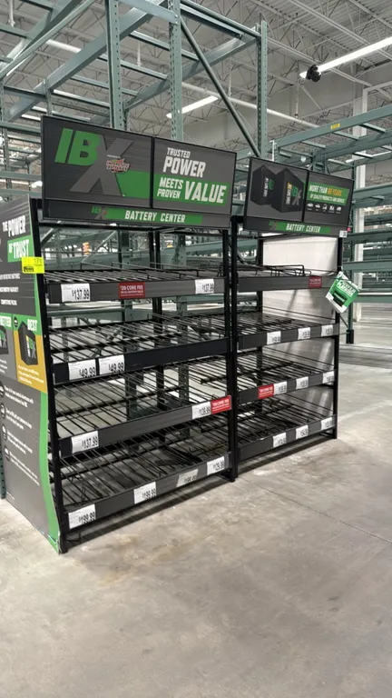 Interstate Batteries IBX retail battery display racks. Features multi-tier gravity-feed wire shelving with dividers, integrated price channel labeling