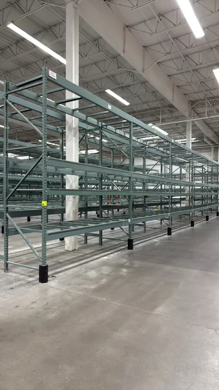 Interlake warehouse racking. Features teardrop punch uprights, horizontal step beams, crossbar pallet supports, and safety lock pins. Finished in gree