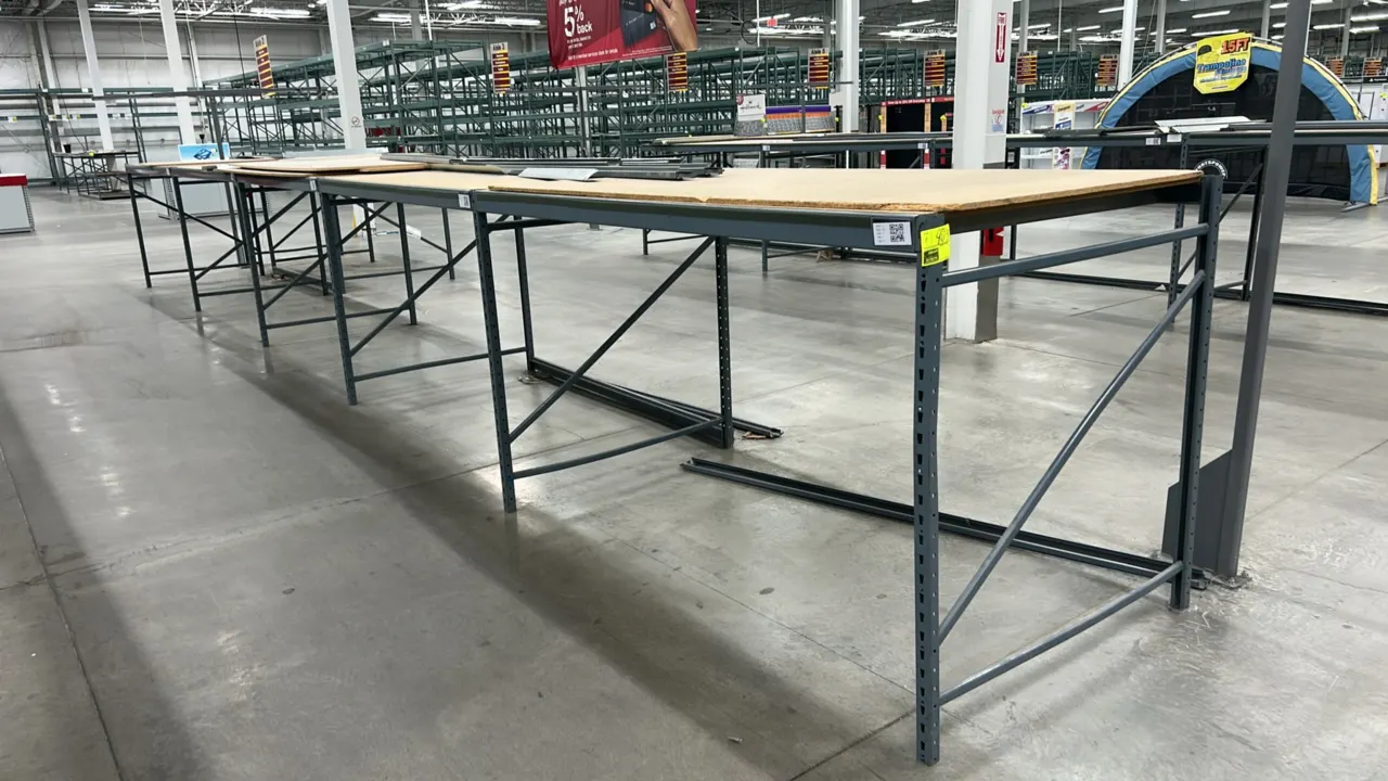 Metal light-duty warehouse racking with corkboard decks. Features gray painted steel upright frames, cross beams, deck supports, and corkboard/composi