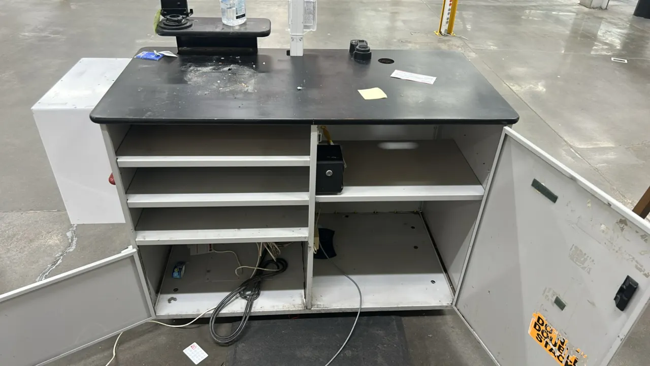 Laminate service stand. Features a black laminate countertop, open shelving, interior storage compartments, an attached side emergency defibrillator c