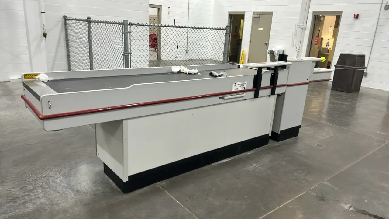 Reynolds UL-2 single belt laminate checkout lane. Features motorized conveyor belt, pull-out check writing platform, protective red bumper guard, and