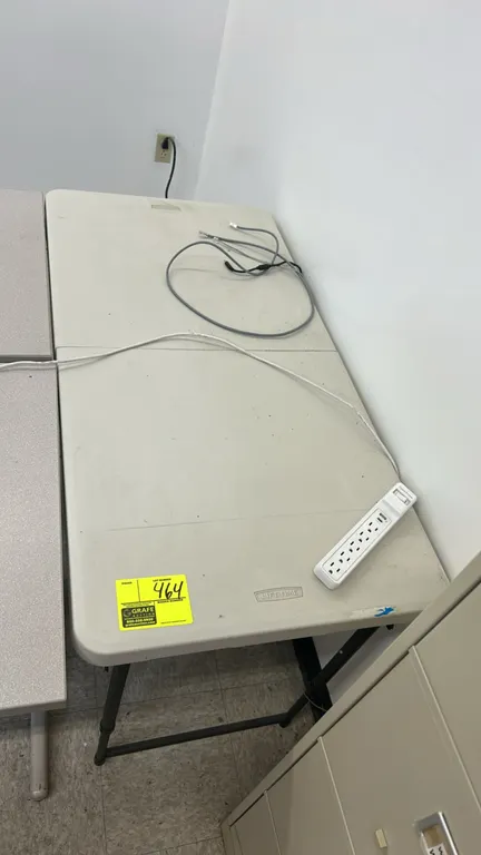 Lifetime folding table. Features a molded polyethylene fold-in-half top and folding metal legs. 4'L. Power strip, cables, and surrounding items not in