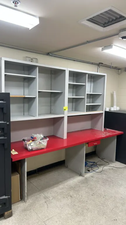 Laminate desk with overhead shelves. Features a red laminate work surface, single center utility drawer, and dual upper hutch sections with adjustable