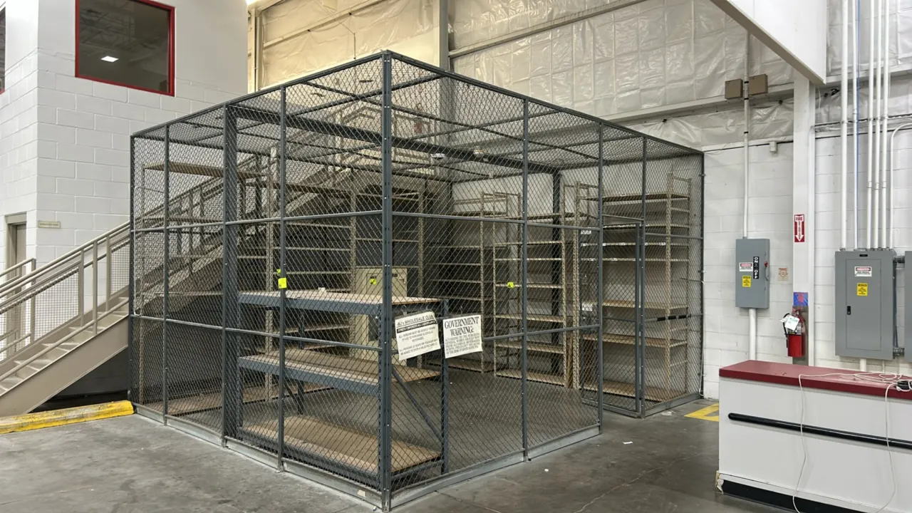 Metal 3-sided security cage with wire mesh ceiling. Features (1) lockable hinged door and steel frame construction. 170" x 205" x 122". Note: Shelving