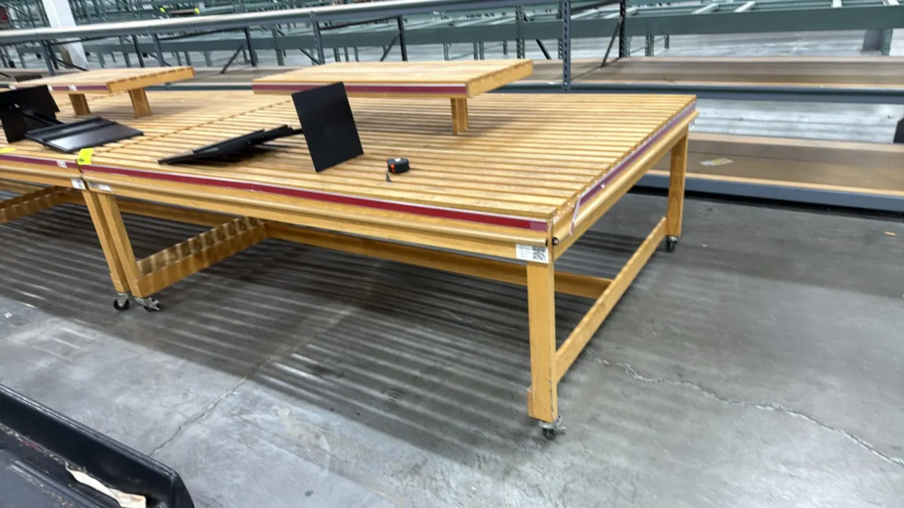Wood slat mobile bakery display table. Features slatted wood display surface, raised wood slat upper display riser, edge bumper trim, and price tag mo