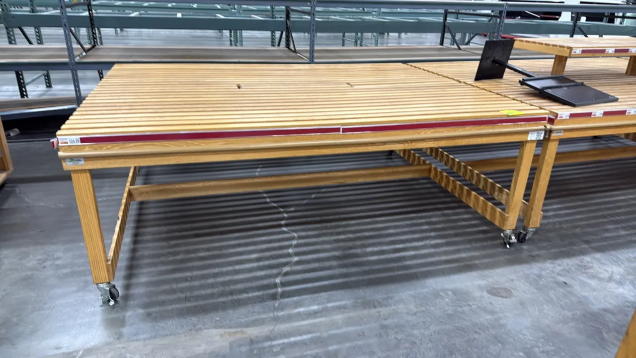 Wood slat portable bakery display table. Features a slatted wood display top, perimeter ticket molding with red accent stripe, and lower wooden suppor