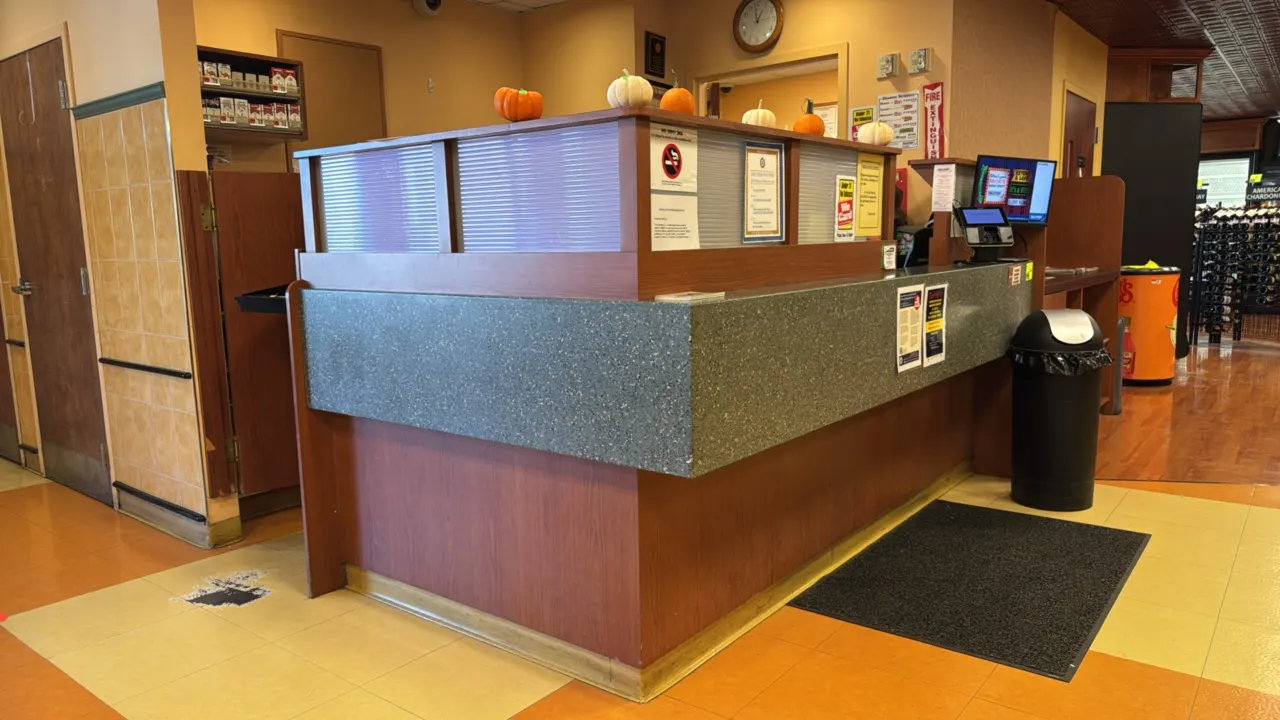 L-shaped laminate wood service counter. Features solid surface countertops, transaction counter with privacy panels, 32" walk-through opening, and int
