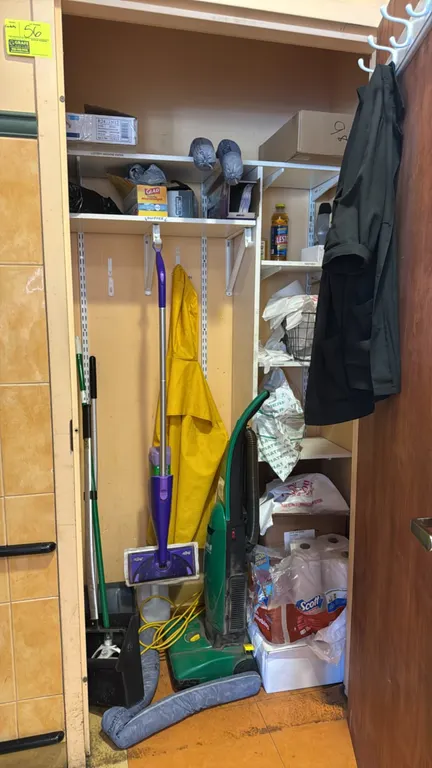 Laminate shelving with metal brackets and assorted cleaning supplies. Features white laminate shelves with slotted metal wall standards and brackets.