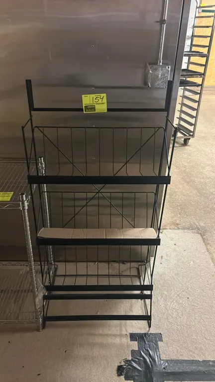 Metal wire multi-tier display rack. Features black finish wire construction with 3 tiered baskets, integrated price tag channels, and a top header sig
