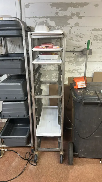 Metal front-load mobile meat platter racks. Features multi-tier angle tray runners. Mounted on swivel casters. Contents not included.