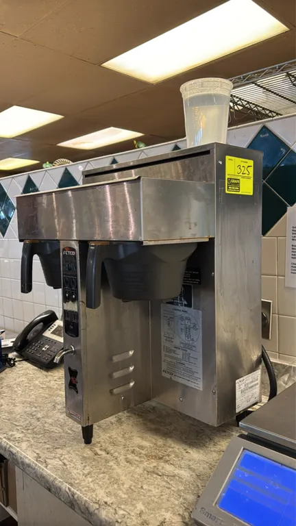 2004 Fetco CBS-2032e Extractor twin coffee brewer. Features stainless steel construction, dual brew heads with brew baskets, and front hot water fauce