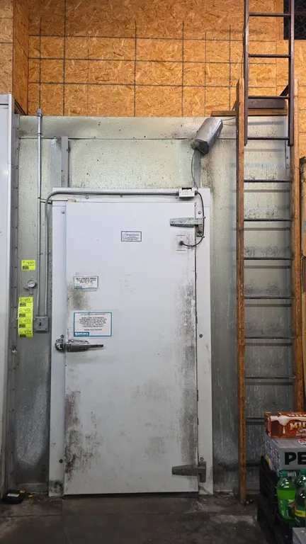 Refrigerated Structures walk-in freezer. Features 38" x 84" entryway door with interior safety release, plastic strip curtain, interior lighting, and