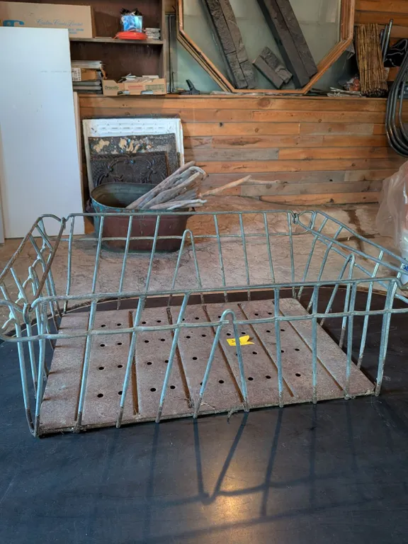 Vintage metal wire milk bottle crate with solid, perforated metal bottom.