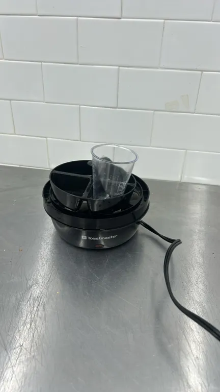 Toastmaster rapid electric egg cooker. Includes clear dome lid, poaching tray insert, and measuring cup. Features corded electric power.