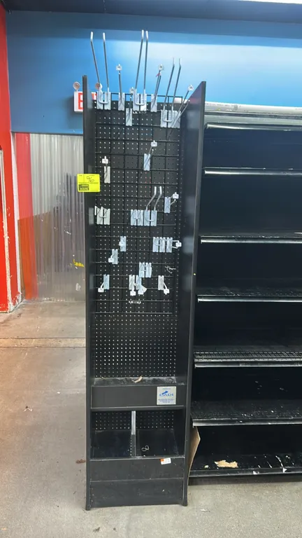 LADI laminate pegboard merchandiser. Features black laminate construction, pegboard backing with wire grid overlay, assorted metal display hooks, and