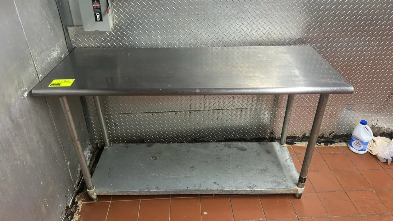 Stainless steel work table. Features a stainless steel top with rolled front and rear edges and a lower undershelf. Dimensions: 5' x 2'. Mounted on tu