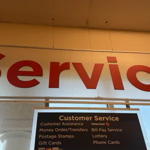Overhead customer service department sign. Features red dimensional lettering reading "Service" on a white rectangular panel with an attached lower cu