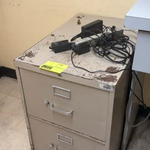 Metal 2-drawer vertical filing cabinet. Features pull handles, thumb latches, and integrated label holders. Note: Shows heavy paint loss and rust on t