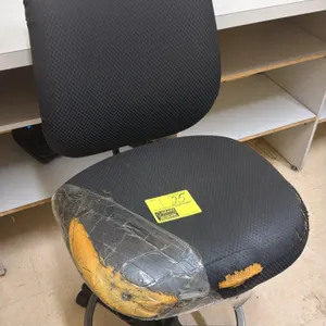 Office drafting chair. Features black fabric upholstery, armless design, and integrated foot ring. Mounted on a 5-star base with casters. Note: Seat u