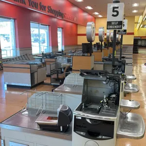 NCR 7350 self-checkout lane. Features stainless steel top, touchscreen monitor, payment terminal mount, bi-optic scanner scale, overhead lane light, a