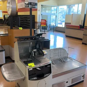 NCR 7350 self-checkout lane. Features stainless steel top, touchscreen monitor, (2) wire bag stands, side shelf, and lane light pole. 7'L. S/N: 30-487