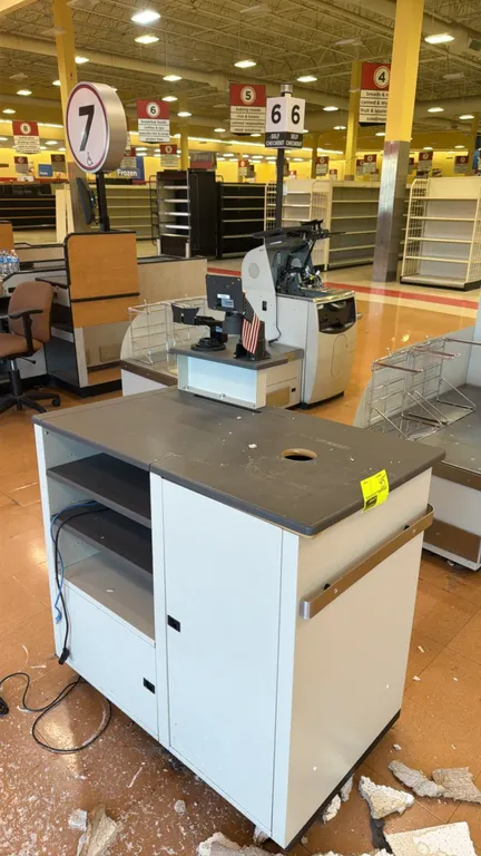 Laminate retail checkout counter. Features a gray laminate countertop with cable pass-through hole, raised upper shelf with POS mounting brackets, low