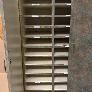 Laminate mail and cash drawer storage cabinet. Features faux-stone laminate finish, two hinged doors, 42 interior sorting slots arranged in three colu